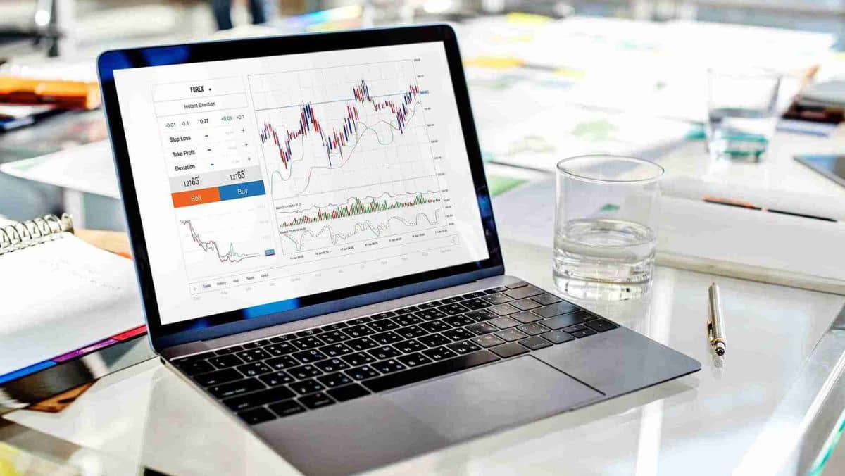 A laptop showing a trading chart positioned on a professional office desk