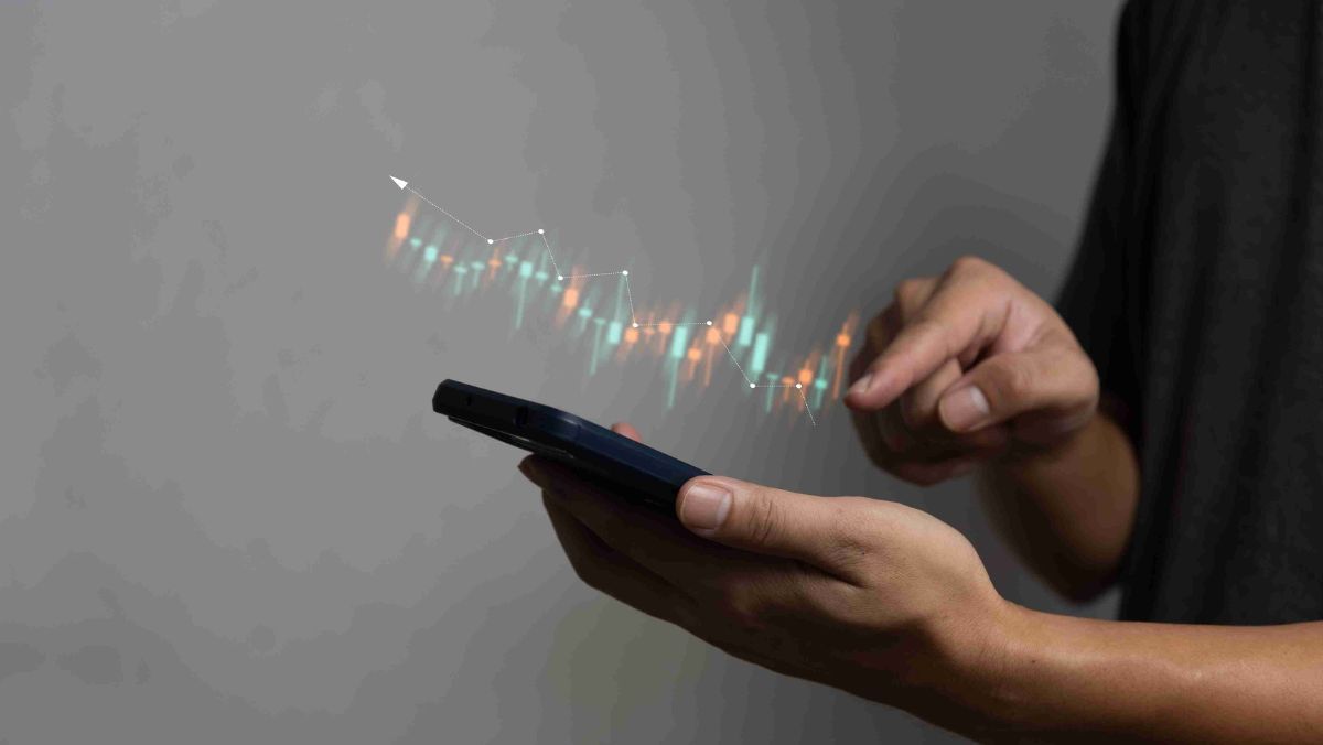 A person using a mobile phone with trading patterns on top of the device screen