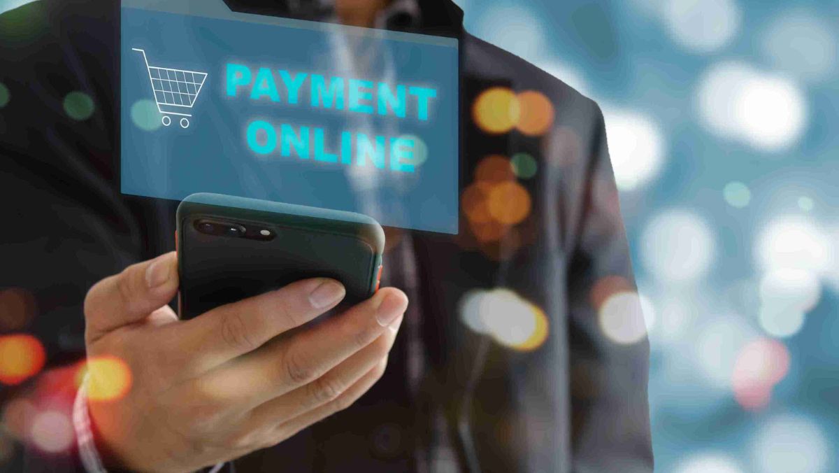 A person with a mobile device displaying a sign that reads Payment Online