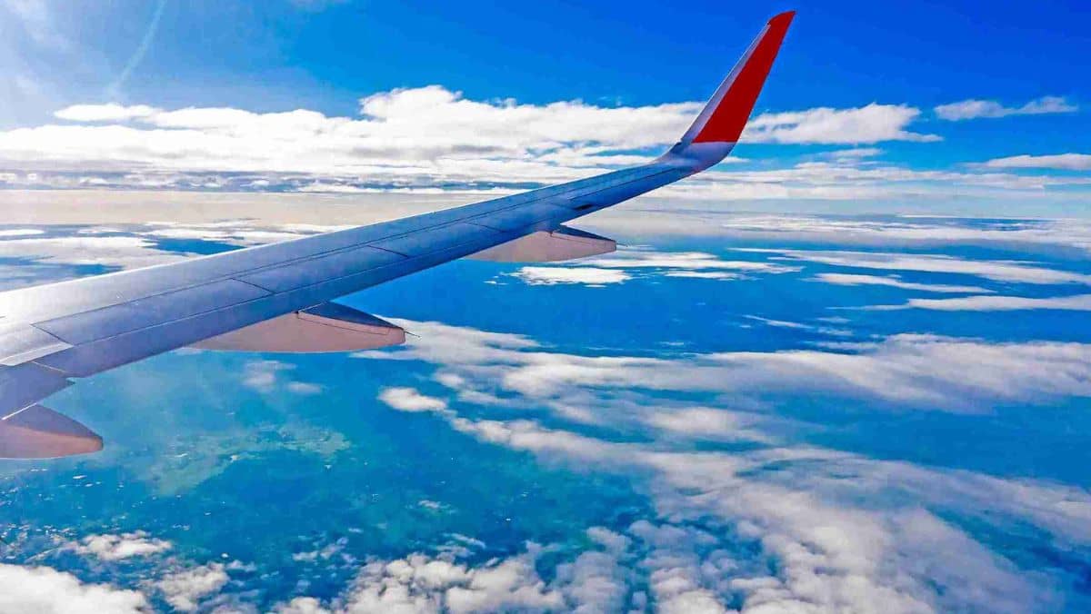 An aircraft soaring through the sky with a view of its right-wing exposed