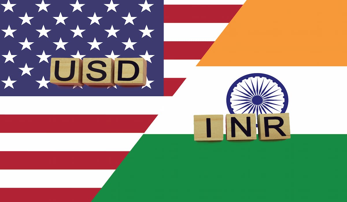 INR A USD currency codes on Indian and American flags, highlighting forex exchange rates.