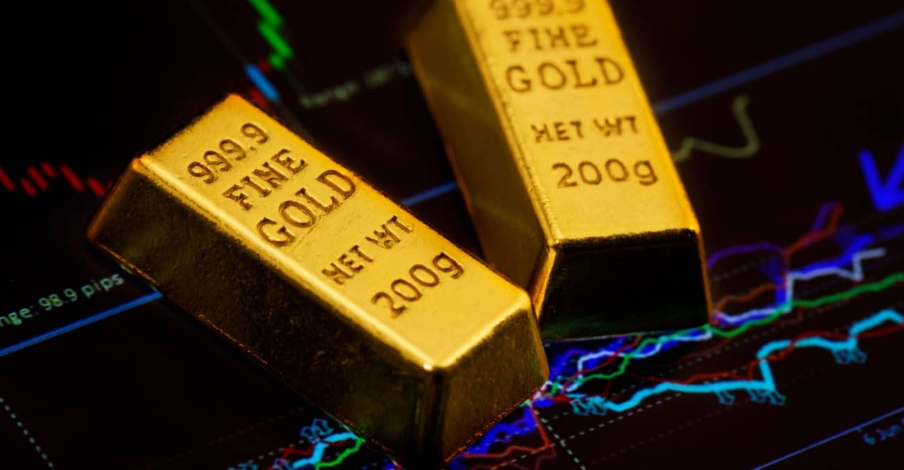 gold bar on the background of a laptop on which there is a trading price chart. Trading gold on the stock exchange and Forex.