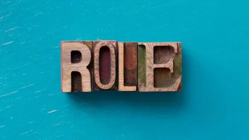 Wooden blocks spelling ROLE on a teal background